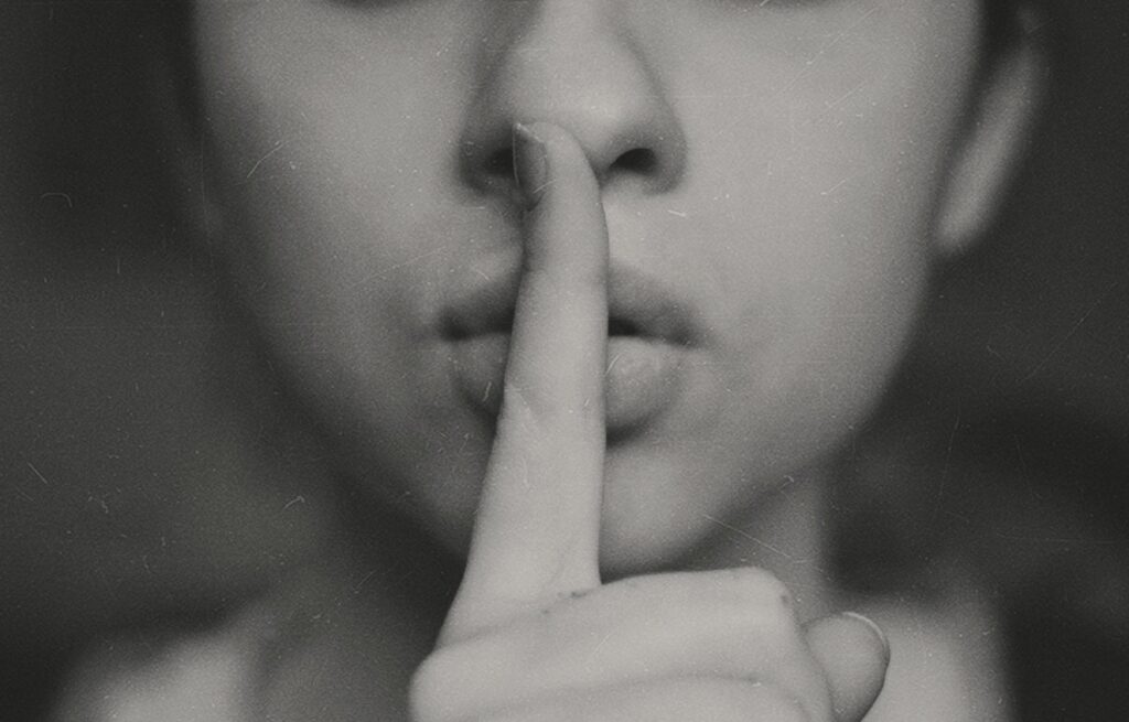 Woman holding a finger in front of her mouth to signal silence.